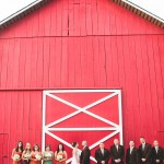 A wedding party in front of a red barn in California